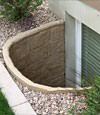 A durable plastic egress window well installed in a rock garden in Dingman.