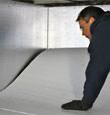 A contractor installing TerraBlock™ floor insulation in a Newton crawl space