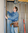 Insulated basement wall panels being placed against a concrete foundation wall in Dingman